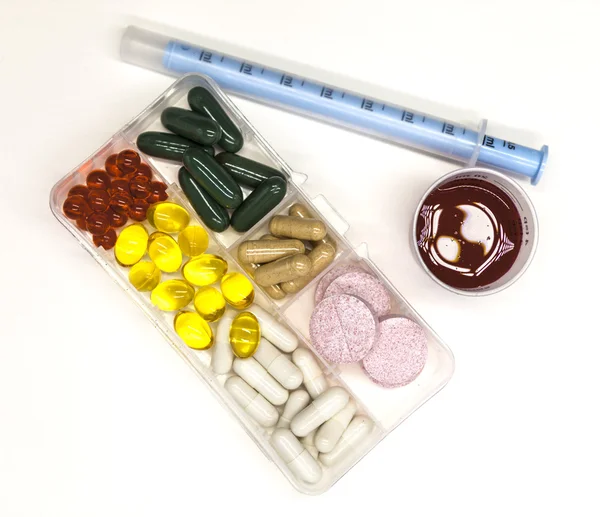 Diferentes píldoras, medicamentos, las píldoras en la caja para medicamentos primer plano con medicamentos con una jeringa sobre fondo blanco . — Foto de Stock