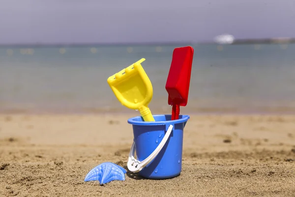 Toys on sandy beach in the foreground and blurred sea in the background. — Stock Photo, Image