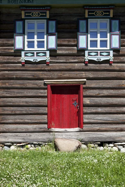 Porta velha vermelha e janela na parede de madeira de uma casa de aldeia. Excelente fundo . — Fotografia de Stock