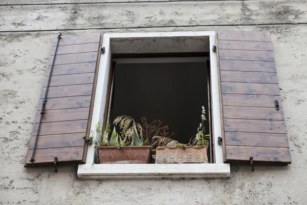 Παλιό παράθυρο με ανοίξετε τα παραθυρόφυλλα με λουλούδια στο περβάζι του παραθύρου στον πέτρινο τοίχο. Ιταλικό χωριό — Φωτογραφία Αρχείου