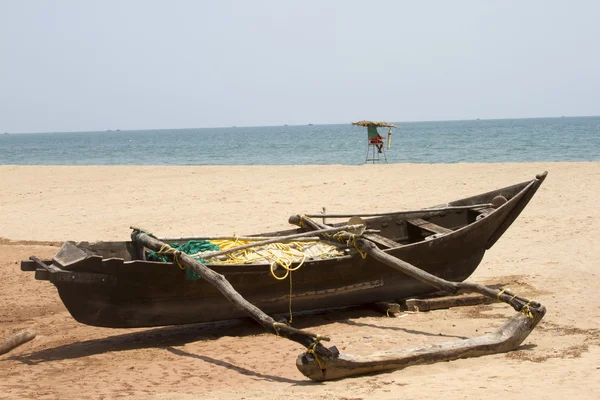 Старая рыбацкая лодка стоит на песчаном пляже. Индия, Гоа — стоковое фото