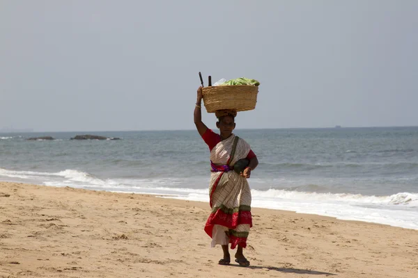 The Indian woman in a sari bears fruit on the head on a beach. India Goa — Stock Photo, Image