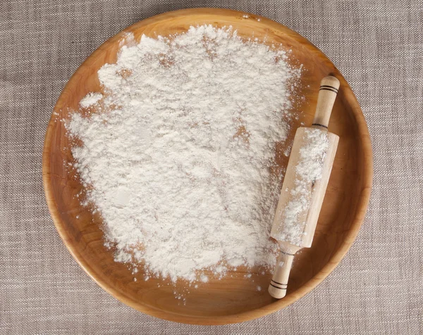 Rolling pin on flour on a wooden tray. — Stock Fotó