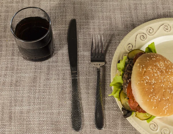 Hamburger frais avec une côtelette de bœuf marbré et légumes frais dans une assiette avec une fourchette et un couteau — Photo