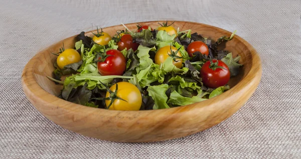 Frischer Salat und rote und gelbe Kirschtomaten auf einem Holztablett — Stockfoto
