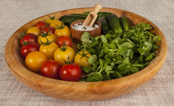 Tomates y pepinos cherry rojos y amarillos frescos, cebollas en una bandeja de madera de estilo rústico . — Foto de Stock