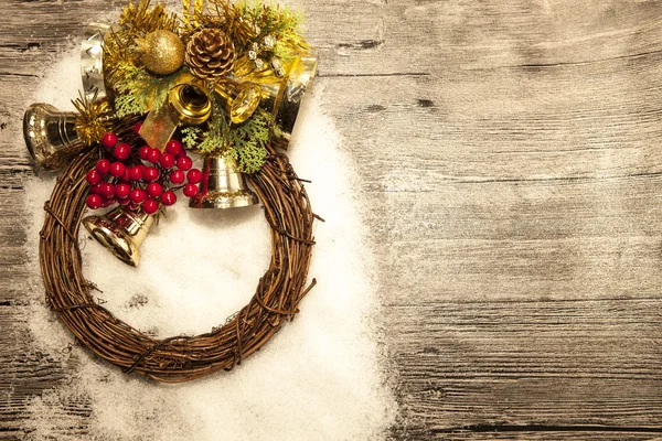 Glittering gold Christmas balls, bells,wreath, and star on wooden background with snow . — Stock Photo, Image