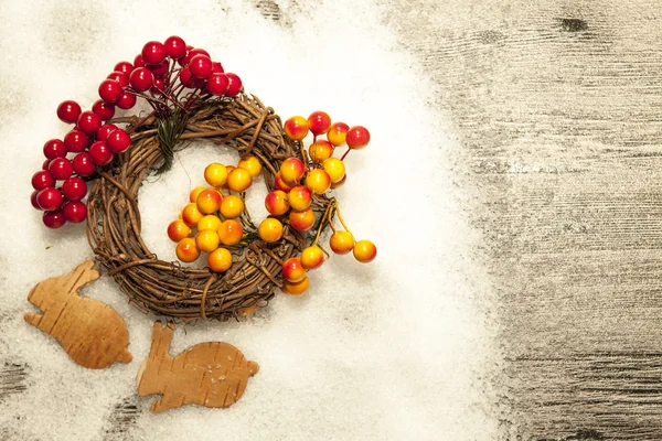 Tarjeta de Navidad con liebres y una pequeña corona de corteza de abedul sobre un fondo de madera . —  Fotos de Stock