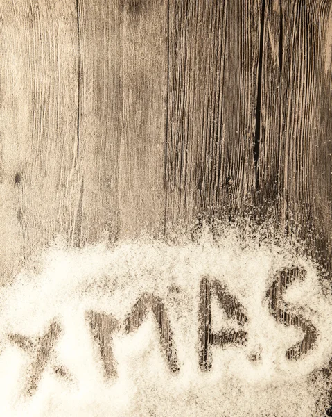 Christmas card with the inscription xmas  in the snow on a wooden background — Stock Fotó