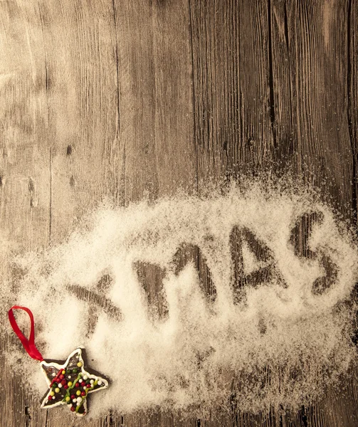Christmas card with the inscription xmas with christmas toys in the snow on a wooden background — Stock Fotó