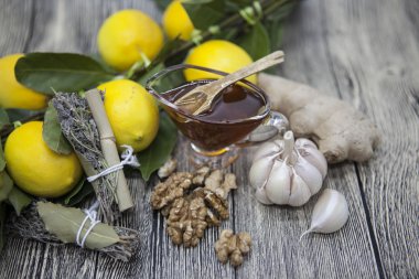 Cam vazoda çiçek bal ve limon provencal otlar ceviz, sarımsak ve zencefil ahşap arka plan üzerinde tahta kaşıkla bileşimi