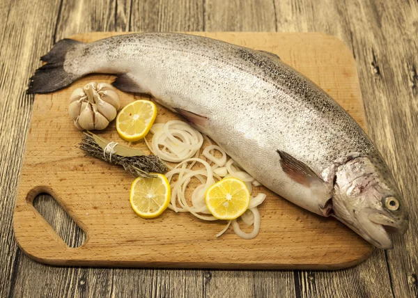 Fresh Norwegian rainbow trout with lemon and onions on a wooden background — Stock Photo, Image