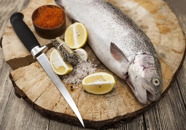 Trota iridea norvegese fresca con caviale rosso limone, sale marino, coltello e cipolle su fondo di legno — Foto Stock