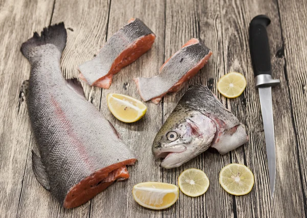 Fresco norvegese bistecche di trota arcobaleno con limone si trova su uno sfondo di legno — Foto Stock