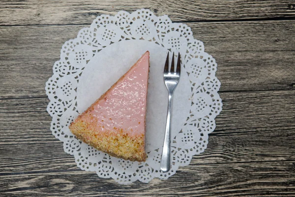 Pedaço doce saboroso fresco de bolo rosa em um guardanapo branco e um garfo de sobremesa em um fundo de madeira — Fotografia de Stock