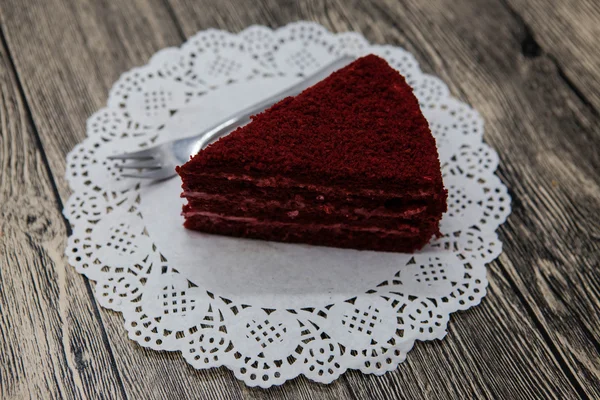 Pedaço doce saboroso fresco de bolo de veludo vermelho, em um guardanapo branco e um garfo de sobremesa em um fundo de madeira — Fotografia de Stock