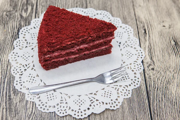 Pedaço doce saboroso fresco de bolo de veludo vermelho, em um guardanapo branco e um garfo de sobremesa em um fundo de madeira — Fotografia de Stock