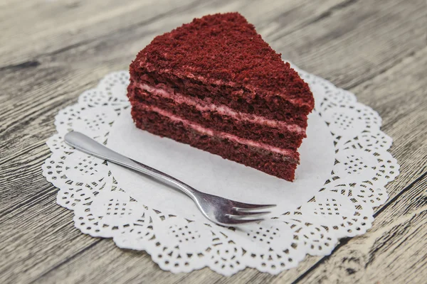 Pedaço doce saboroso fresco de bolo de veludo vermelho, em um guardanapo branco e um garfo de sobremesa em um fundo de madeira — Fotografia de Stock