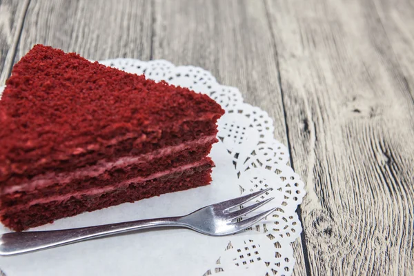 Pedaço doce saboroso fresco de bolo de veludo vermelho, em um guardanapo branco e um garfo de sobremesa em um fundo de madeira — Fotografia de Stock