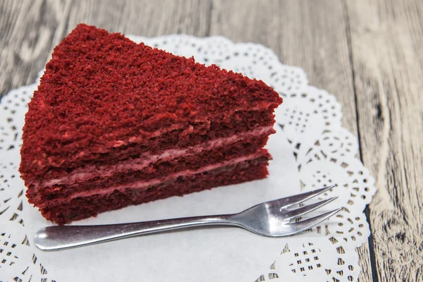 Pedaço doce saboroso fresco de bolo de veludo vermelho, em um guardanapo branco e um garfo de sobremesa em um fundo de madeira — Fotografia de Stock