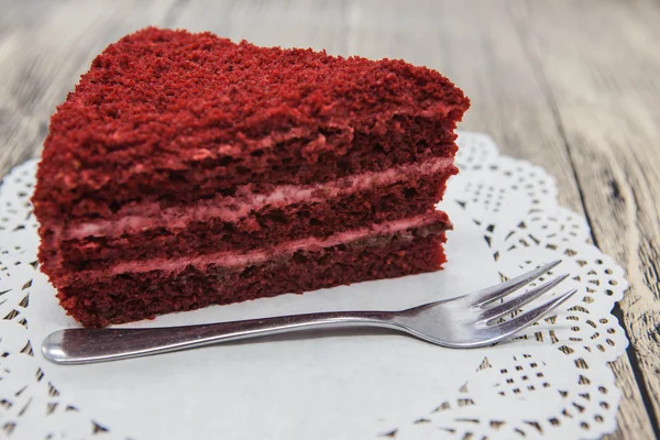 Pedaço doce saboroso fresco de bolo de veludo vermelho, em um guardanapo branco e um garfo de sobremesa em um fundo de madeira — Fotografia de Stock