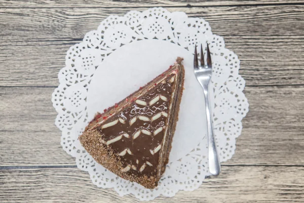 Frische leckere süße Stück Schokoladenkuchen auf einer weißen Serviette und eine Dessertgabel auf einem hölzernen Hintergrund — Stockfoto
