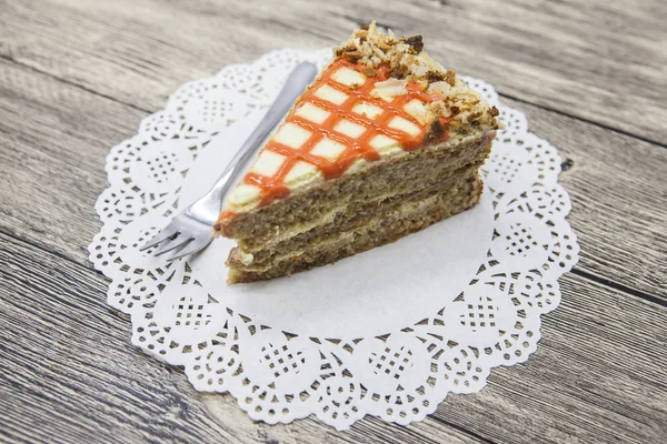 Fresh tasty sweet piece of  carrot cake on a white napkin and a dessert fork on a wooden background