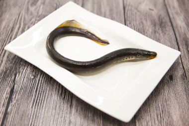Fresh live fish lamprey on porcelain plate with lemon.