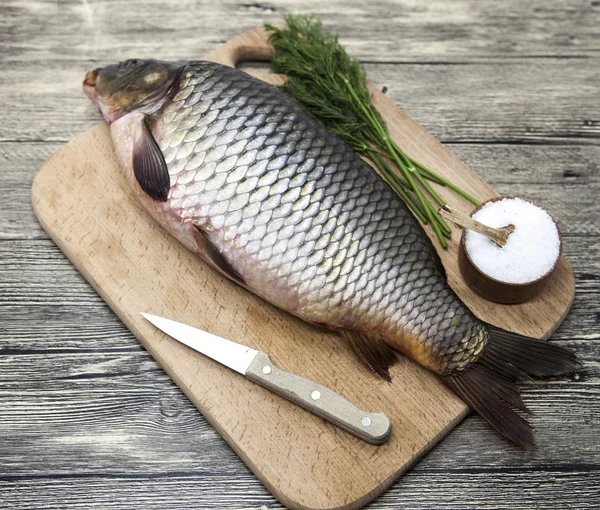 Una grande carpa fresca di pesce vivo sdraiato su una tavola di legno con sale e aneto . — Foto Stock