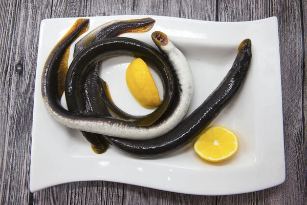 Свежая живая рыба миноги на фарфоровой тарелке с лимоном . — стоковое фото