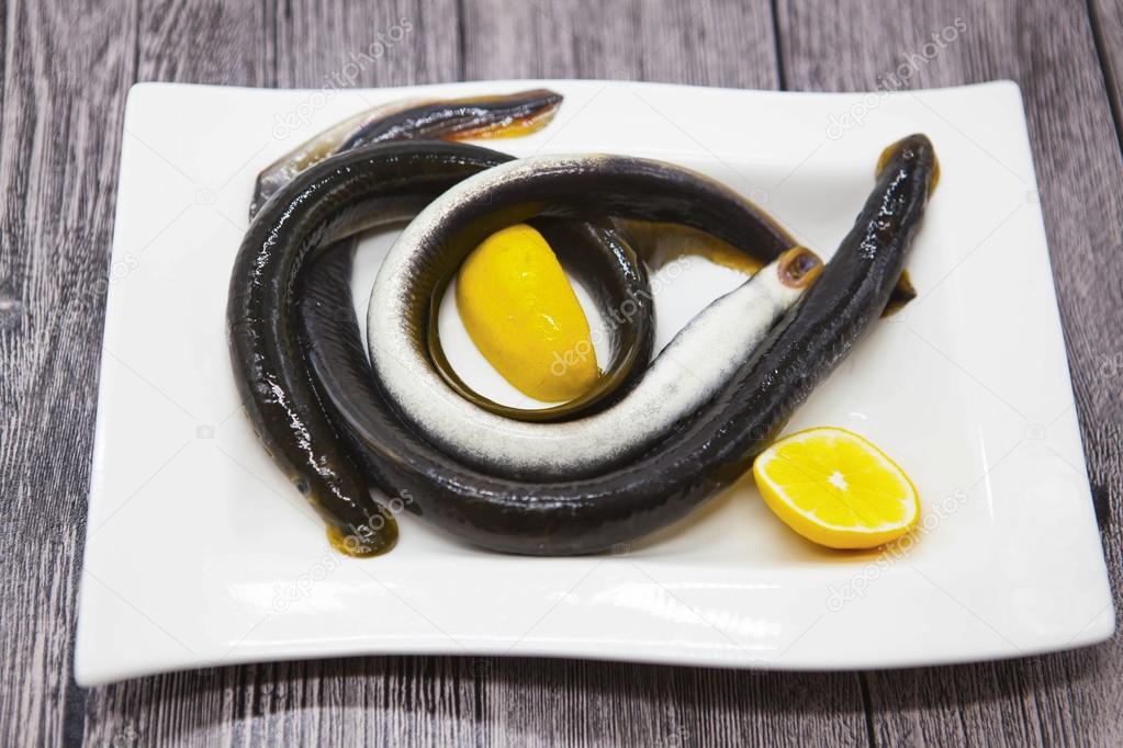 Fresh live fish lamprey on porcelain plate with lemon.
