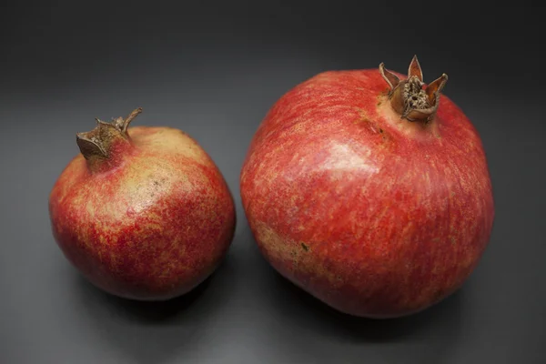 Two fruit juicy Spanish pomegranate on a dark background. — Stock Photo, Image