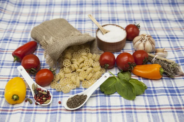 Rotelle pasta italiana para la creación: tomates cherry, aceite de oliva, salsa balsámica, ajo, especias, sal marina, ensalada en una mesa rústica — Foto de Stock