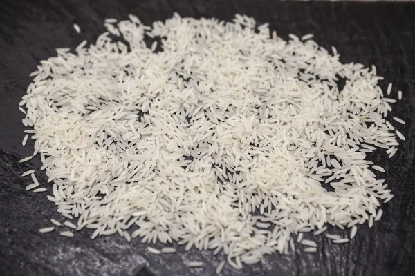 White friable crude Thai rice on a stone black background. — Stockfoto