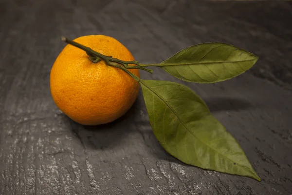 Свежий сочный вкусный сицилийский мандарин с лиственной ветвью на каменном фоне . — стоковое фото