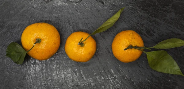 Свежие сочные вкусные сицилийские мандарины с лиственной ветвью на каменном фоне . — стоковое фото