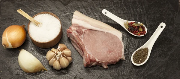 Pieces of fresh raw  pork  onion, garlic, spices, salt on the stone plate — Stock Fotó