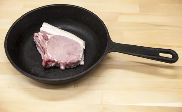 A piece of delicious fresh raw pork close-up on a cast iron skillet on the table rustic kitchen — Stock Fotó