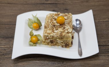 Fresh delicious diet cake with berry Physalis at Dukan Diet on a porcelain plate with a spoon on a wooden background.