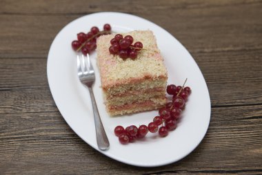 Fresh delicious diet cake with berry red currant at Dukan Diet on a porcelain plate with a spoon on a wooden background.