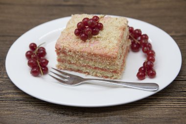 Fresh delicious diet cake with berry red currant at Dukan Diet on a porcelain plate with a spoon on a wooden background.