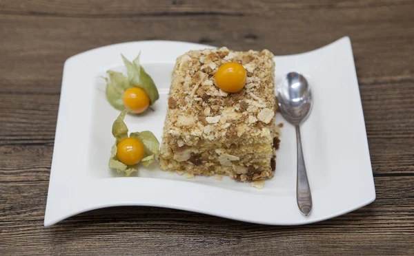 Bolo de dieta delicioso fresco com baga Physalis em Dukan Diet em uma placa de porcelana com uma colher em um fundo de madeira . — Fotografia de Stock