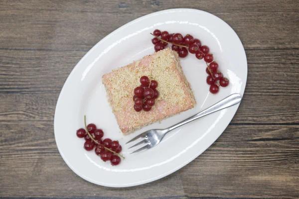 Frischen leckeren Diätkuchen mit Beeren rote Johannisbeere bei Dukan Diät auf einem Porzellanteller mit einem Löffel auf einem hölzernen Hintergrund. — Stockfoto