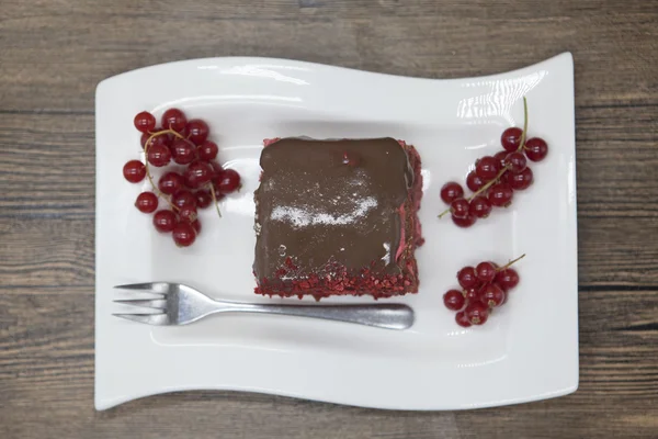 Red Velvet, fresh delicious diet cake with red currant at Dukan Diet on a porcelain plate with a spoon on a wooden background