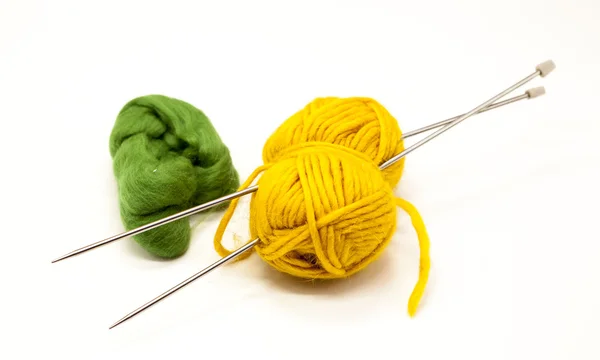 Kulki zielone i żółte przędzy na drutach z ramionami na białym tle. — Zdjęcie stockowe