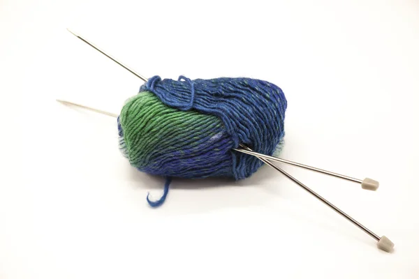 Bolas verdes e azuis de fios para tricotar com raios sobre um fundo branco . — Fotografia de Stock