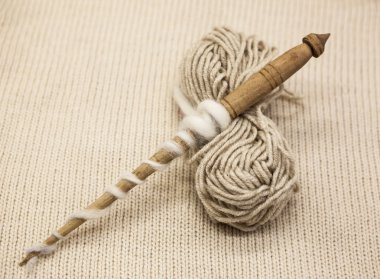 Old wooden spindle with a ball of wool thread for the manufacture of woolen threads on a tissue background clipart