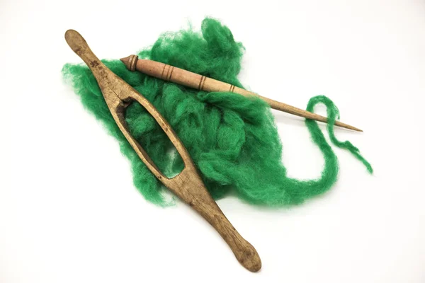 Lã verde e fuso velho close-up no fundo branco. Ferramentas para tricotar de lã — Fotografia de Stock