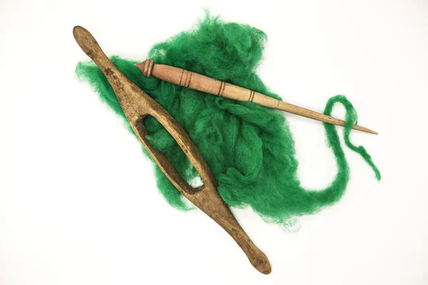 Green wool and old spindle close-up on white background. Tools for knitting of wool — Stock Photo, Image