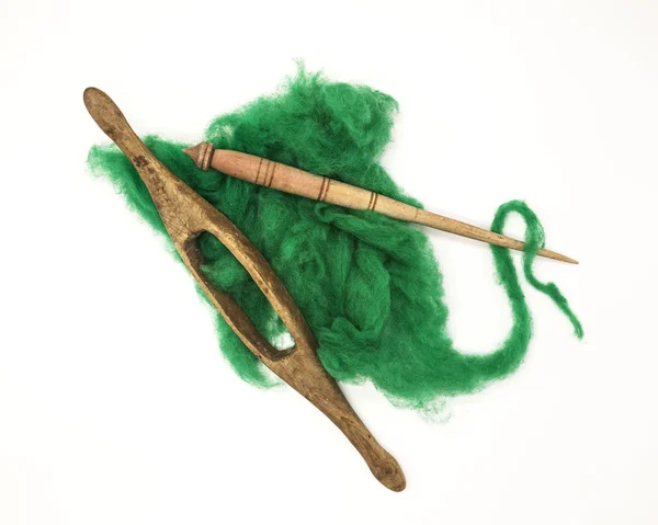 Green wool and old spindle close-up on white background. Tools for knitting of wool — Stock Photo, Image